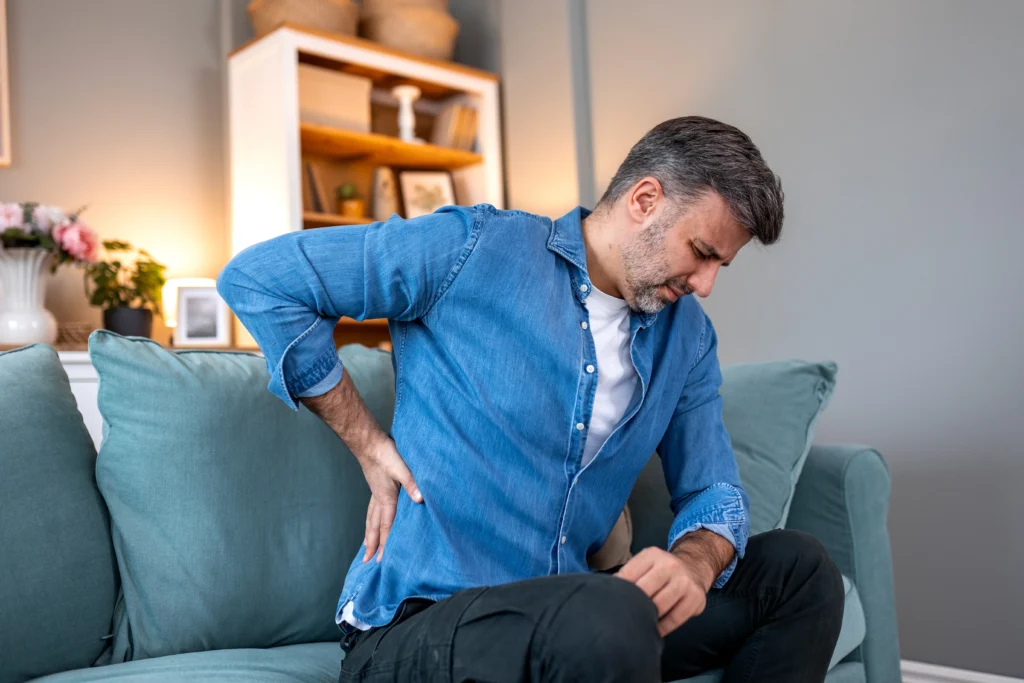 man experiencing sciatic pain while he's sitting on the couch